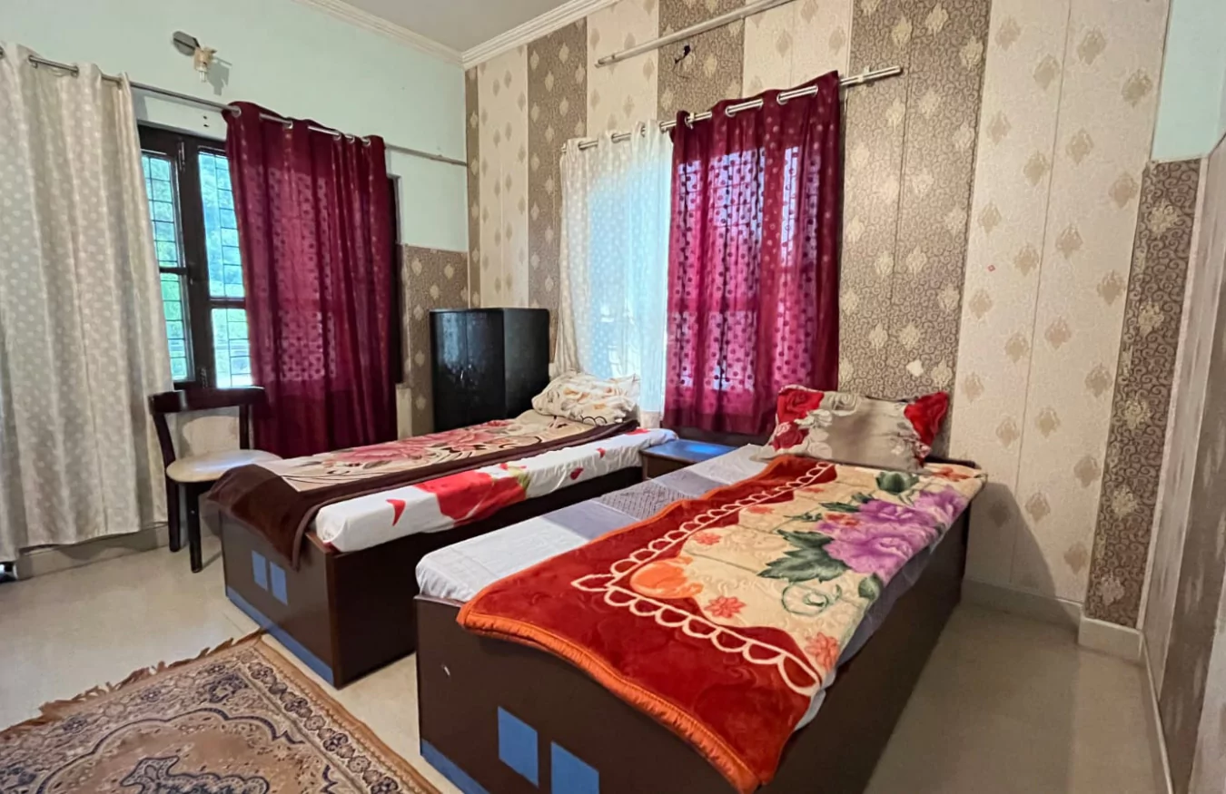 A well-lit twin-sharing room with comfortable bedding.